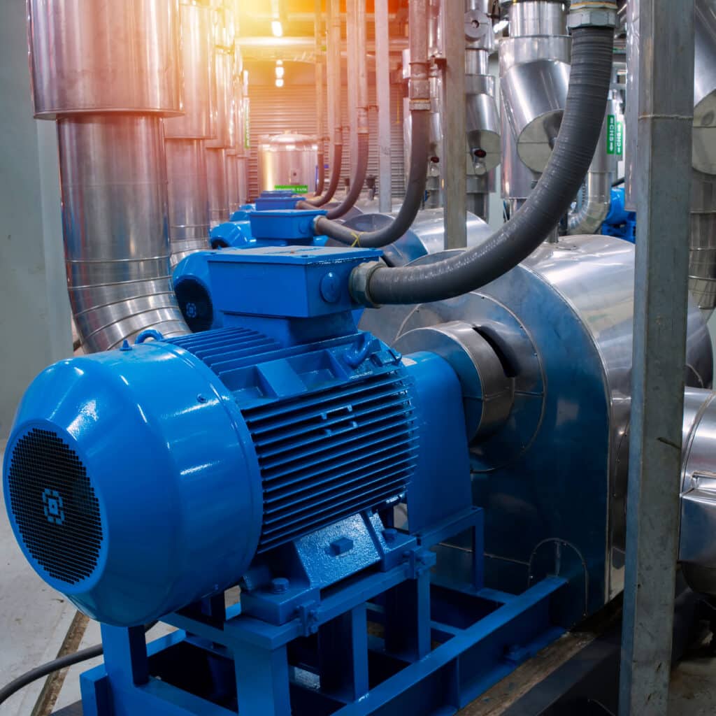 Moteur Électrique Industriel et Tuyauterie en Acier Moteur électrique industriel bleu et soufflerie dans une usine avec tuyauterie en acier inoxydable et conduits.