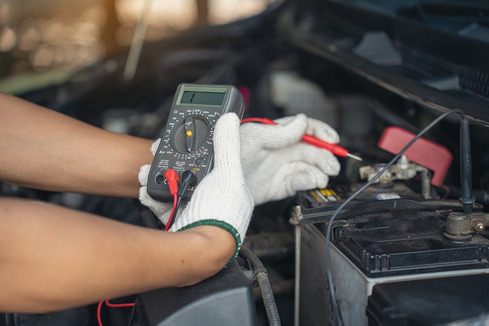 Comment tester une batterie de voiture avec un multimètre Test de tension d'une batterie de voiture avec un multimètre numérique par un mécanicien ganté.